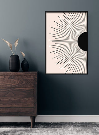 Black sunrise art poster with minimalist sunburst design, displayed above a dark wood dresser in a modern living room.