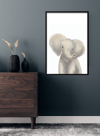 Framed poster of a cute gray elephant illustration for children, displayed above a wooden dresser in a modern room.
