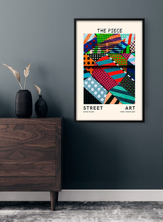 Framed Street Art - The Piece Plakat featuring colorful abstract patterns, displayed on a dark gray wall above a dresser.