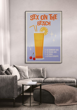 Framed Sex on the Beach cocktail wallchart with recipe, displayed above a modern gray couch in a living room.