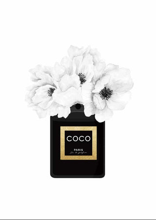 Black Chanel perfume bottle with white flowers blooming from the top, Coco Paris label in gold and black.