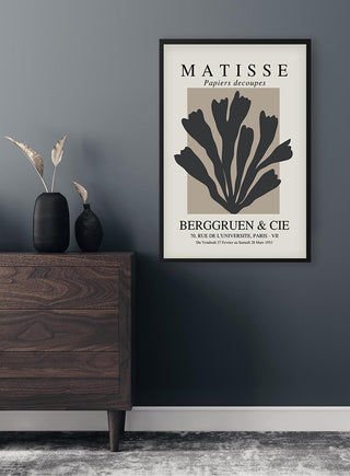Black Papier Decoupe poster in a modern frame, displayed above a wooden dresser against a dark wall.