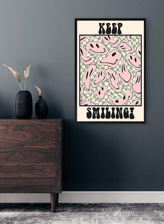 Keep Smiling! poster with abstract pink smiling faces on a patterned background, hanging above a wooden dresser.