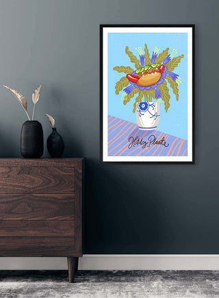 Framed Hotdog Plante artwork by Nina Broen displayed on a dark wall above a wooden dresser.