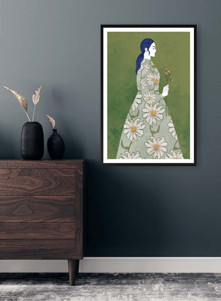 Framed "Search For Your Smile - Elara Monet" art print of a woman in a floral dress hanging on a dark wall.
