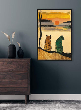 Framed art print of two tigers resting and watching a sunset, displayed on a dark gray wall above a wooden dresser.