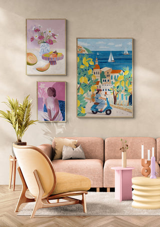 Poster of a woman on a scooter overlooking the Amalfi coast, displayed above a pastel sofa in a modern living room.