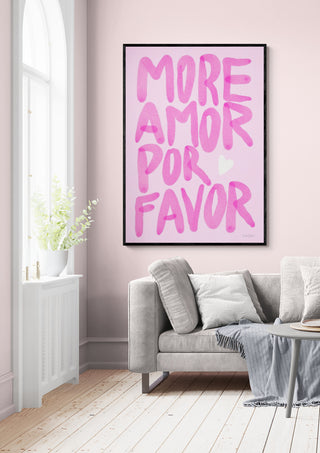 Framed "More Amor Por Favor" Baroo Bloom print in pink tones displayed above a sofa in a bright living room.