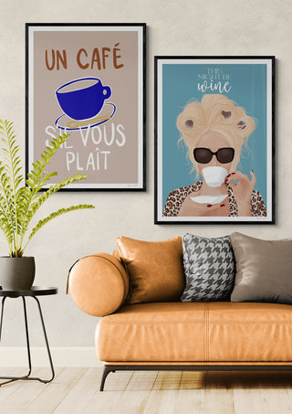 Framed wall art featuring a blue coffee cup and a woman drinking coffee, styled above a tan sofa.