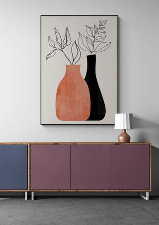Abstract vase and leaf artwork by Boris Draschoff above a modern sideboard with a table lamp.