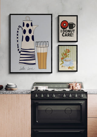 Framed "I donut care!" print hanging in a modern kitchen above a stove, alongside other art.