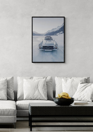 Framed art of a retro silver car driving on a frozen lake, displayed above a modern couch in a living room.