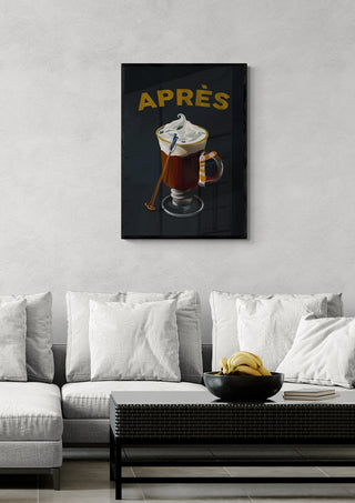 Wall art of a hot cocoa cocktail with whipped cream and spoon, labeled "APRÈS," hanging above a modern sofa.
