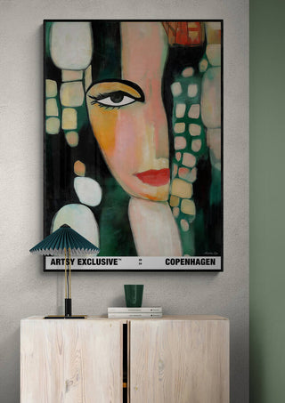 Abstract portrait of a woman's face in bold colors, displayed above a light wooden cabinet; Femininity by Martin Zen.