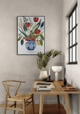 Framed Elara Monet floral artwork hangs above a desk with decor in a cozy, sunlit room.